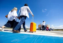 Passageiros caminham pela pista de aeroporto carregando malas e embarcam em aeronave, representando o aumento de passageiros nos aeroportos de Santa Cataina