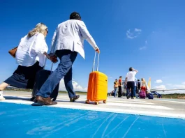 Santa Catarina ultrapassa 8,5 milhões de passageiros nos aeroportos em 2025 Passageiros caminham pela pista de aeroporto carregando malas e embarcam em aeronave, representando o aumento de passageiros nos aeroportos de Santa Cataina