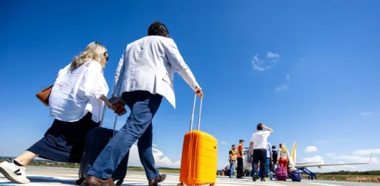 Passageiros caminham pela pista de aeroporto carregando malas e embarcam em aeronave, representando o aumento de passageiros nos aeroportos de Santa Cataina