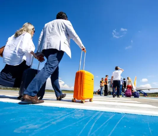 Passageiros caminham pela pista de aeroporto carregando malas e embarcam em aeronave, representando o aumento de passageiros nos aeroportos de Santa Cataina