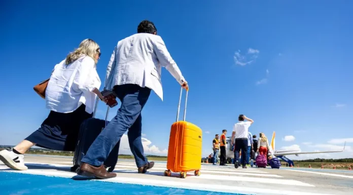Santa Catarina ultrapassa 8,5 milhões de passageiros nos aeroportos em 2025 Passageiros caminham pela pista de aeroporto carregando malas e embarcam em aeronave, representando o aumento de passageiros nos aeroportos de Santa Cataina