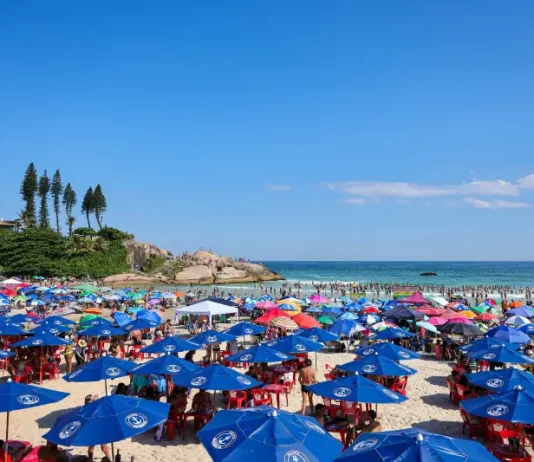 Semana começa com tempo firme e termina com calor intenso e temporais em Santa Catarina Imagem ilustra dia de calor intenso no litoral de Santa Catarina, com praia lotada, guarda-sóis abertos e grande concentração de pessoas aproveitando o tempo firme.