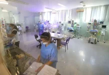 Profissionais da área da saúde atuam em ambiente hospitalar com equipamentos médicos, imagem usada para ilustrar o concurso público da Secretaria de Estado da Saúde de Santa Catarina.