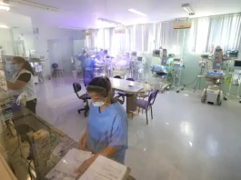 Profissionais da área da saúde atuam em ambiente hospitalar com equipamentos médicos, imagem usada para ilustrar o concurso público da Secretaria de Estado da Saúde de Santa Catarina.