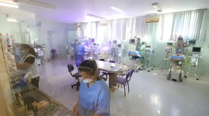 Profissionais da área da saúde atuam em ambiente hospitalar com equipamentos médicos, imagem usada para ilustrar o concurso público da Secretaria de Estado da Saúde de Santa Catarina.