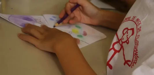 Criança pintando em aula na Escolinha de Arte da FCC