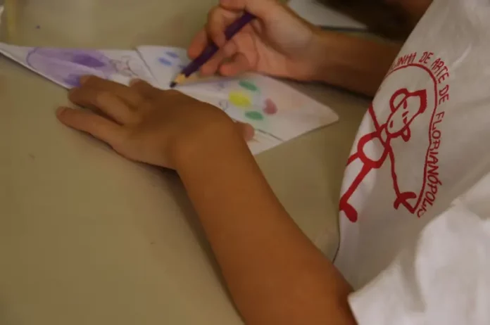 Criança pintando em aula na Escolinha de Arte da FCC