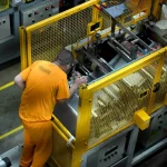 Trabalho prisional em SC gera R$ 32 milhões em 2025 e reduz gastos do Estado Detento operando uma máquina em unidade prisional, ilustrando o programa de trabalho remunerado de presos em Santa Catarina.