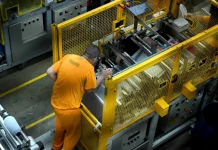 Detento operando uma máquina em unidade prisional, ilustrando o programa de trabalho remunerado de presos em Santa Catarina.