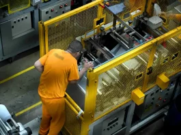 Detento operando uma máquina em unidade prisional, ilustrando o programa de trabalho remunerado de presos em Santa Catarina.