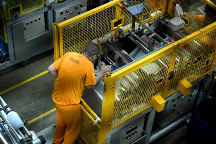 Detento operando uma máquina em unidade prisional, ilustrando o programa de trabalho remunerado de presos em Santa Catarina.