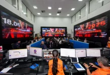 Centro de operações da Defesa Civil de Santa Catarina durante simulado de gestão de desastres, com equipes monitorando dados, coordenando ações e acompanhando ocorrências em tempo real.