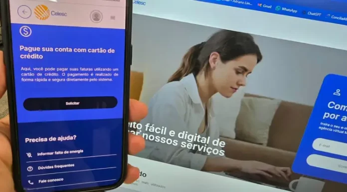 Celesc libera pagamento da conta de luz com cartão de crédito e parcelamento em até 21 vezes Aplicativo da Celesc exibido em um celular mostra a opção de pagamento da conta de luz com cartão de crédito, enquanto ao fundo aparece a Agência Web da companhia, ilustrando os canais digitais disponíveis para os clientes.