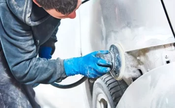 Homem utilizando lixadeira para preparar carro, simbolizando participante do curso gratuito de funilaria e pintura em São José