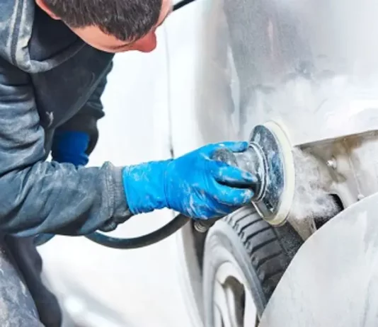 Homem utilizando lixadeira para preparar carro, simbolizando participante do curso gratuito de funilaria e pintura em São José