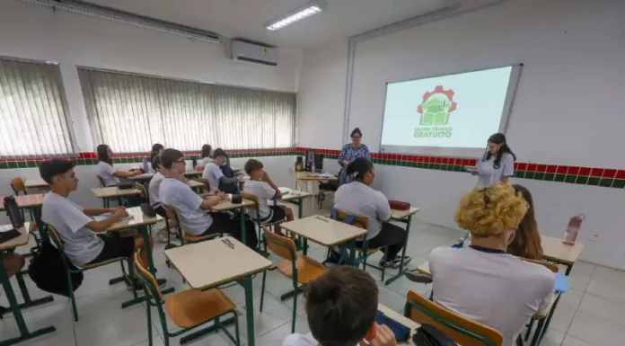 Estudantes assistem aula de cursos técnicos gratuitos em sala de escola pública, com professores orientando a formação profissional e a preparação para o mercado de trabalho.