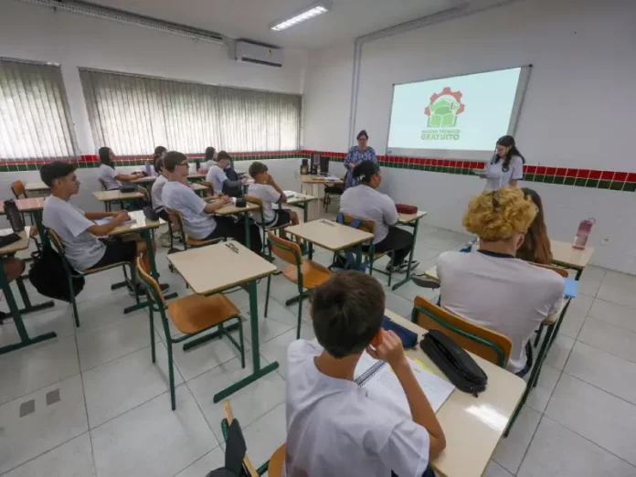 Estudantes assistem aula de cursos técnicos gratuitos em sala de escola pública, com professores orientando a formação profissional e a preparação para o mercado de trabalho.
