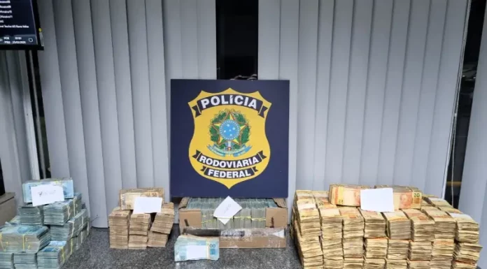Dinheiro em espécie apreendido em ocorrência na BR-101 organizado sobre mesa, durante ação em que a PRF apreende R$ 2 milhões na rodovia.