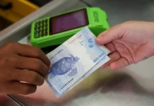 Pessoa realiza pagamento em dinheiro diante de máquina de cartão, imagem que representa acesso a crédito facilitado por programas como Pronampe SC e Juro Zero