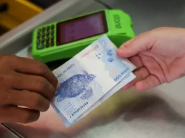 Pessoa realiza pagamento em dinheiro diante de máquina de cartão, imagem que representa acesso a crédito facilitado por programas como Pronampe SC e Juro Zero