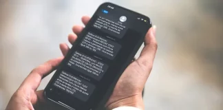 Pessoa segurando celular na mão lendo alerta via SMS da Defesa Civil
