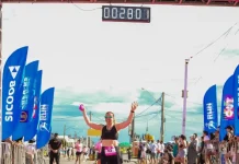 No Dia Internacional da Mulher, Florianópolis recebe a 2ª edição do Sicoob Run Mulher Participante cruza a linha de chegada do Sicoob Run Mulher, celebrando a conclusão da corrida e incentivando a prática esportiva e o bem-estar feminino.