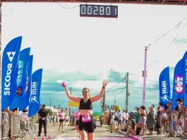 Participante cruza a linha de chegada do Sicoob Run Mulher, celebrando a conclusão da corrida e incentivando a prática esportiva e o bem-estar feminino.