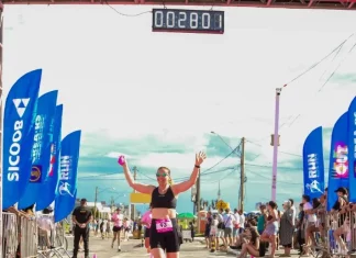Participante cruza a linha de chegada do Sicoob Run Mulher, celebrando a conclusão da corrida e incentivando a prática esportiva e o bem-estar feminino.