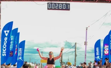 Participante cruza a linha de chegada do Sicoob Run Mulher, celebrando a conclusão da corrida e incentivando a prática esportiva e o bem-estar feminino.
