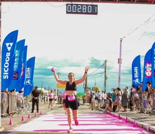 Participante cruza a linha de chegada do Sicoob Run Mulher, celebrando a conclusão da corrida e incentivando a prática esportiva e o bem-estar feminino.