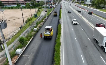 Obras de triplicação da SC-401 em Florianópolis mostram máquinas asfaltando nova faixa da rodovia, com veículos circulando nas pistas ao lado, evidenciando a ampliação da capacidade de tráfego e a melhoria da mobilidade no acesso ao Norte da Ilha.
