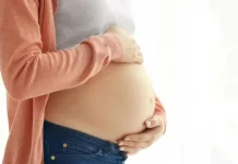 Curso para gestantes em Florianópolis arrecada doações para a APAE de Palhoça Mulher grávida segura a barriga com as mãos, representando gestação e o cuidado materno, em contexto de curso para gestantes em Florianópolis.