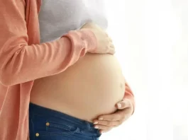 Curso para gestantes em Florianópolis arrecada doações para a APAE de Palhoça Mulher grávida segura a barriga com as mãos, representando gestação e o cuidado materno, em contexto de curso para gestantes em Florianópolis.