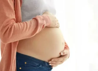 Mulher grávida segura a barriga com as mãos, representando gestação e o cuidado materno, em contexto de curso para gestantes em Florianópolis.