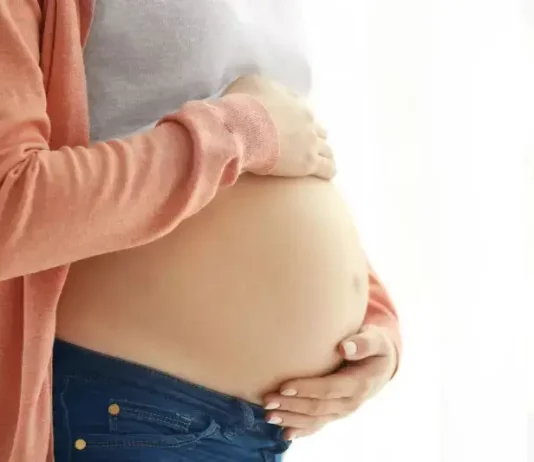 Mulher grávida segura a barriga com as mãos, representando gestação e o cuidado materno, em contexto de curso para gestantes em Florianópolis.