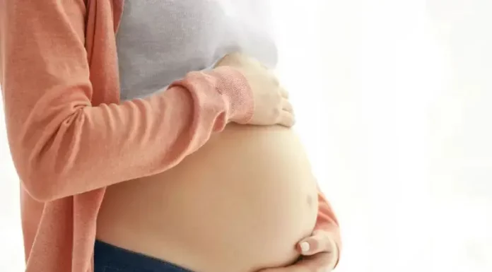Mulher grávida segura a barriga com as mãos, representando gestação e o cuidado materno, em contexto de curso para gestantes em Florianópolis.