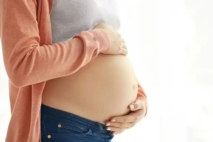 mulher_grvida1 Mulher grávida segura a barriga com as mãos, representando gestação e o cuidado materno, em contexto de curso para gestantes em Florianópolis.