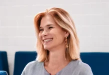 Angela Albino sorrindo, sentada e segurando um celular, durante anúncio de filiação ao PDT em SC