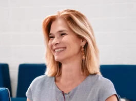 Angela Albino sorrindo, sentada e segurando um celular, durante anúncio de filiação ao PDT em SC