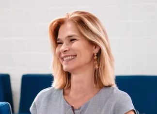 Angela Albino sorrindo, sentada e segurando um celular, durante anúncio de filiação ao PDT em SC