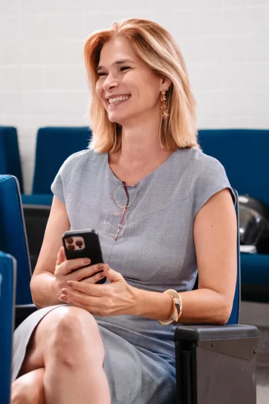 Angela Albino sorrindo, sentada e segurando um celular, durante anúncio de filiação ao PDT em SC