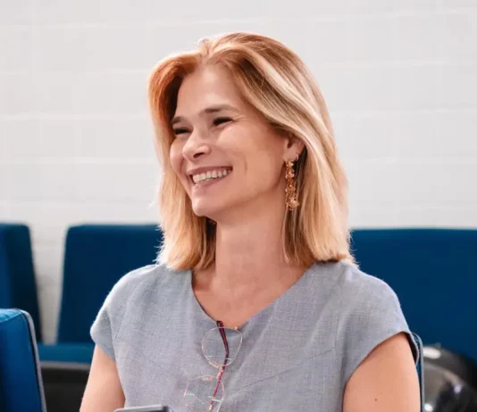 Angela Albino sorrindo, sentada e segurando um celular, durante anúncio de filiação ao PDT em SC