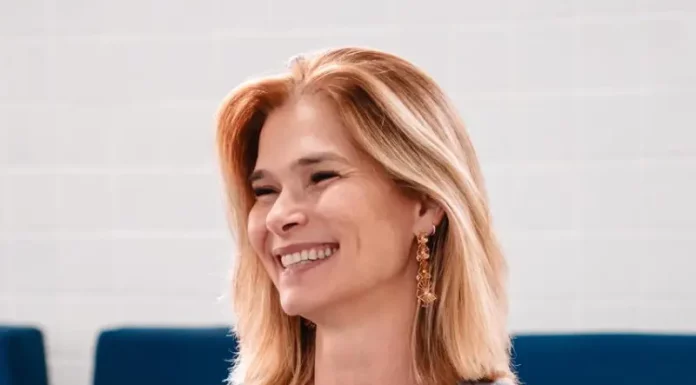 Angela Albino sorrindo, sentada e segurando um celular, durante anúncio de filiação ao PDT em SC