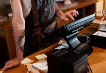 Bares e restaurantes em Santa Catarina têm verão abaixo do esperado Funcionário opera o caixa no balcão de um estabelecimento, ilustrando o movimento e os desafios financeiros enfrentados pelos bares e restaurantes de Santa Catarina durante a temporada de verão.