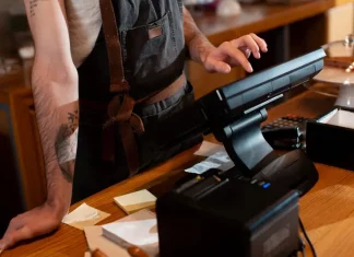 Bares e restaurantes em Santa Catarina têm verão abaixo do esperado Funcionário opera o caixa no balcão de um estabelecimento, ilustrando o movimento e os desafios financeiros enfrentados pelos bares e restaurantes de Santa Catarina durante a temporada de verão.