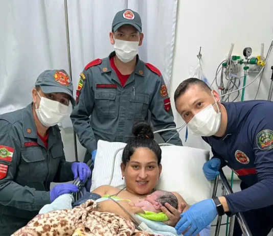 Bombeiros realizam parto em SC: equipe posa com mãe segurando recém-nascido.