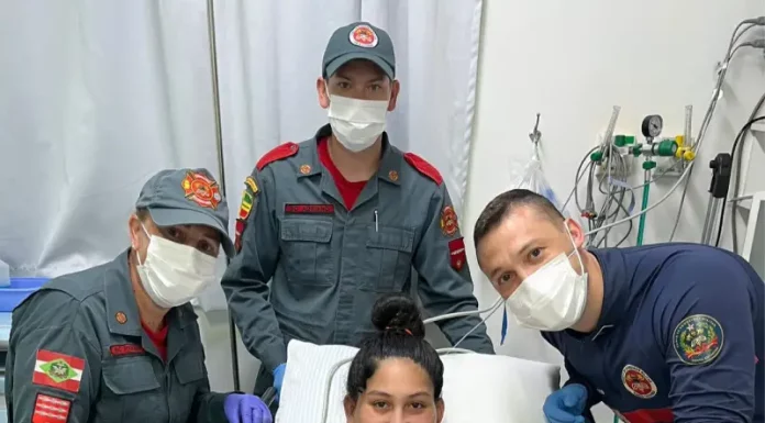 Bombeiros realizam parto em SC: equipe posa com mãe segurando recém-nascido.