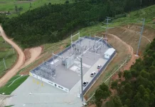 Vista aérea de uma subestação de energia elétrica instalada em área rural de Santa Catarina, cercada por vegetação e estradas de terra. A estrutura, com transformadores, torres e equipamentos de distribuição, representa os investimentos das cooperativas de energia na ampliação e modernização da rede elétrica, garantindo mais segurança energética e qualidade no fornecimento, especialmente para produtores e municípios do interior.