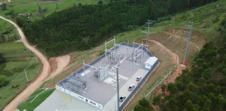 Vista aérea de uma subestação de energia elétrica instalada em área rural de Santa Catarina, cercada por vegetação e estradas de terra. A estrutura, com transformadores, torres e equipamentos de distribuição, representa os investimentos das cooperativas de energia na ampliação e modernização da rede elétrica, garantindo mais segurança energética e qualidade no fornecimento, especialmente para produtores e municípios do interior.