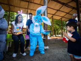 Representantes da Fundação Somar, incluindo um com fantasia de coelho, entregam chocolates a crianças, mostrando onde doar chocolate em Florianópolis durante a campanha de Páscoa.